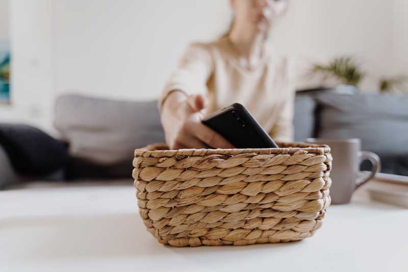 Minimalismo digital. Mujer deja el teléfono en una cesta