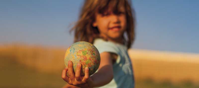 Niña sostiene bola del mundo. Políticas familiares
