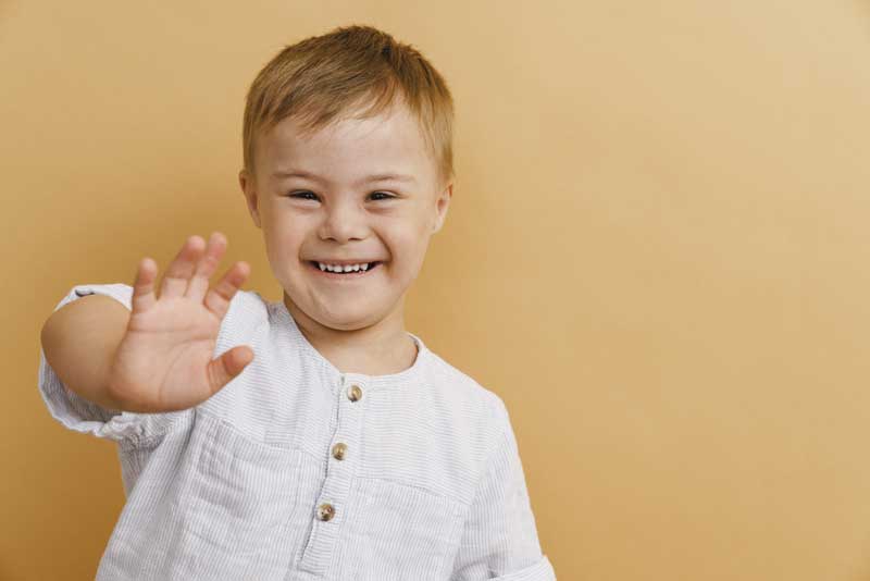 Niño síndrome de down saluda sonriente