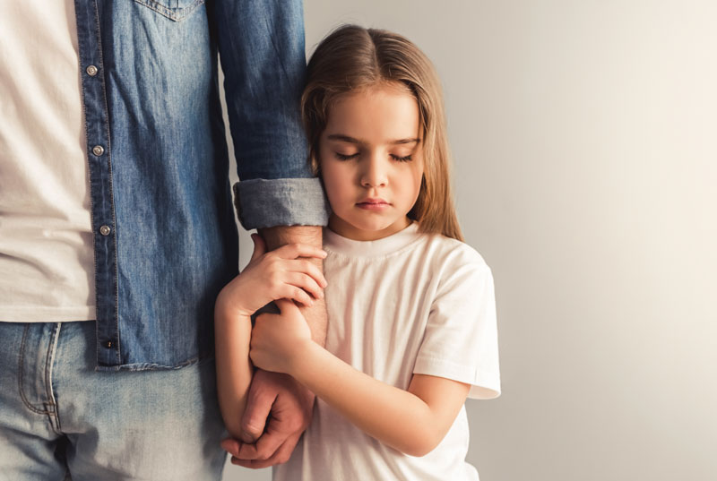 Niña agarra a su padre del brazo