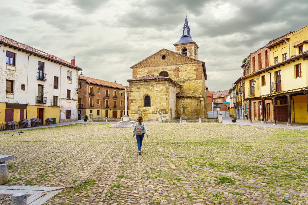 Woman walking through the old Plaza del Grano with its medieval church in Leon, Spain.