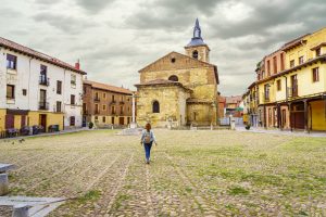 Woman walking through the old Plaza del Grano with its medieval church in Leon, Spain.
